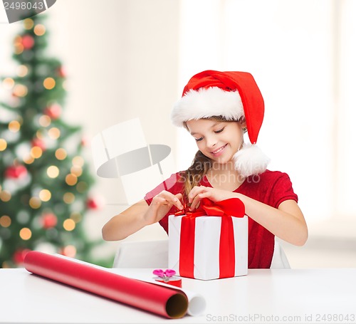 Image of smiling girl in santa helper hat with gift box