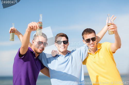 Image of friends on the beach with bottles of drink