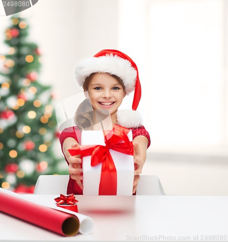 Image of smiling girl in santa helper hat with gift box