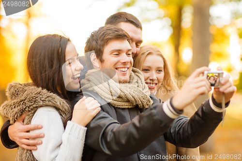 Image of group of friends with photo camera in autumn park