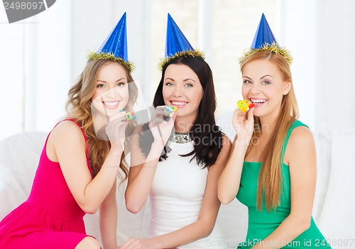 Image of three smiling women in hats blowing favor horns