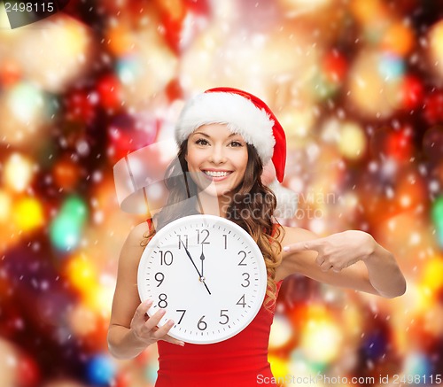 Image of woman in santa helper hat with clock showing 12