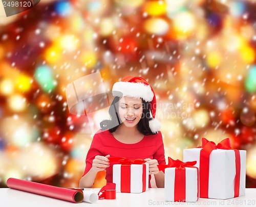 Image of woman in santa helper hat with many gift boxes