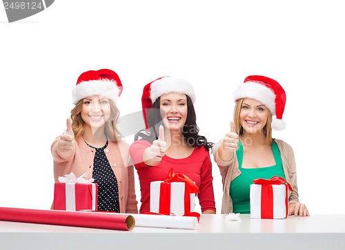 Image of smiling women in santa helper hats with gift boxes