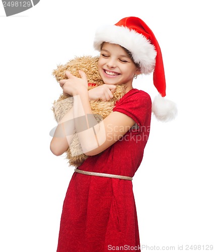 Image of smiling girl in santa helper hat with teddy bear