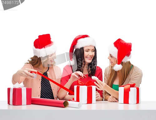 Image of smiling women in santa helper hats with gift boxes