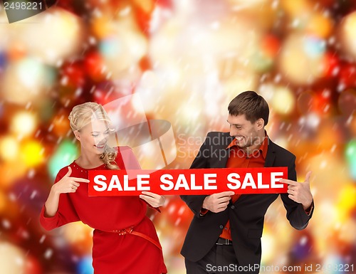 Image of smiling woman and man with red sale sign