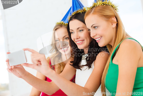 Image of three smiling women in hats having fun with camera