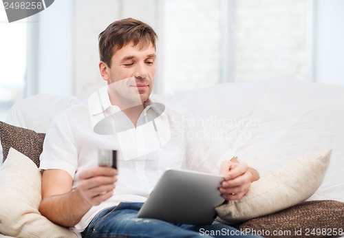 Image of man with tablet pc and credit card at home