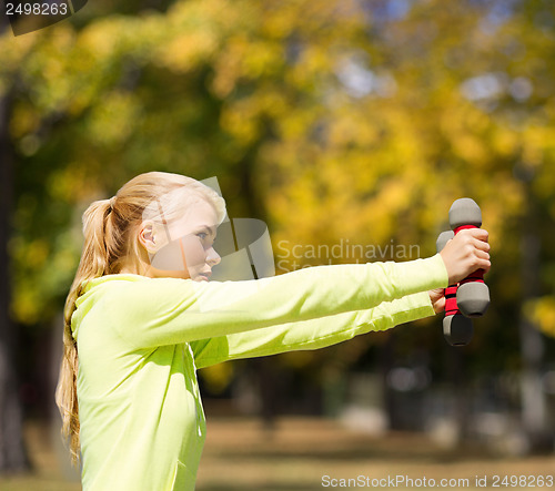 Image of sporty woman with light dumbbells outdoors