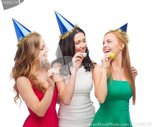 Image of three smiling women in hats blowing favor horns