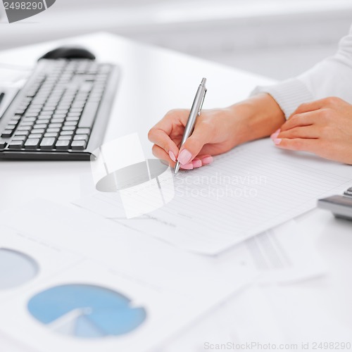 Image of businesswoman working with calculator in office