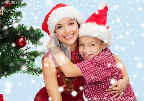 Image of happy mother and child boy in santa helper hats