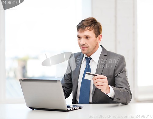 Image of man with laptop and credit card in office
