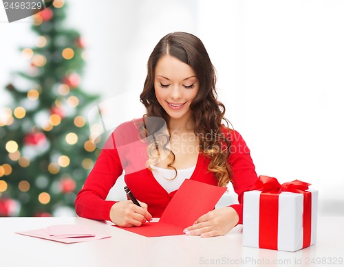 Image of smiling woman in red clothes with postcard