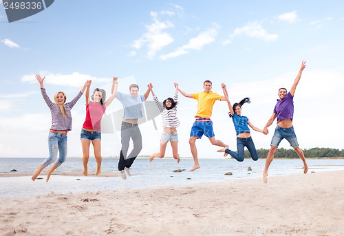 Image of group of friends jumping on the beach