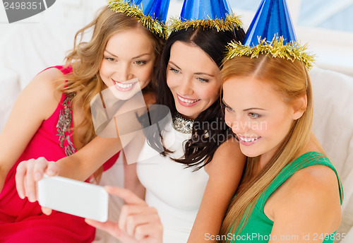 Image of three smiling women in hats having fun with camera