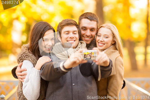 Image of group of friends with photo camera in autumn park