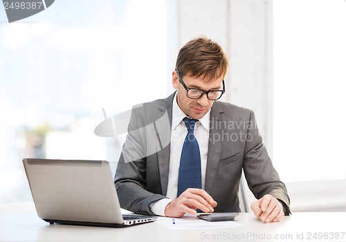 Image of businessman with computer, papers and calculator