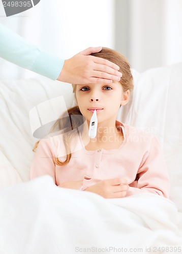 Image of ill girl child with thermometer and caring mother