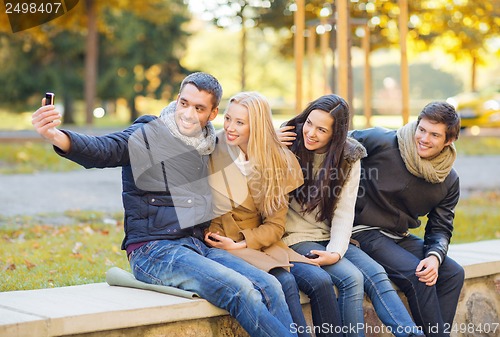 Image of group of friends with photo camera in autumn park