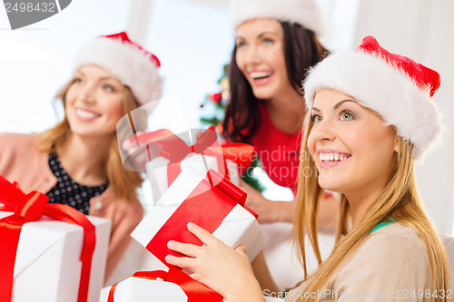 Image of women in santa helper hats with many gift boxes