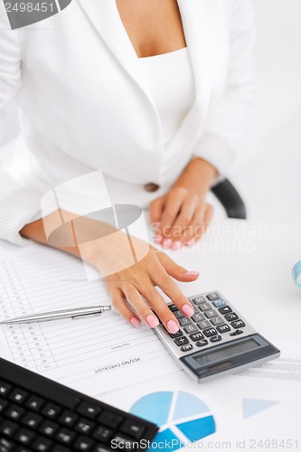 Image of woman hand with calculator and papers