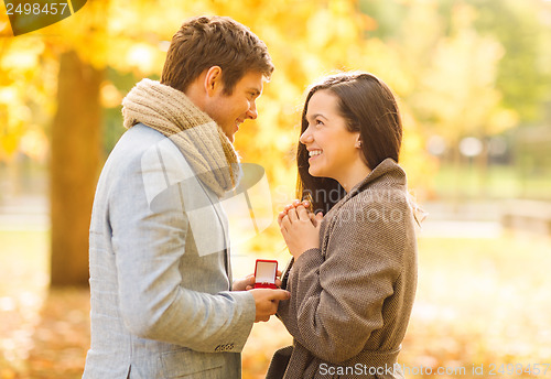 Image of man proposing to a woman in the autumn park