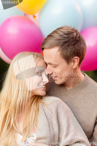 Image of couple with colorful balloons kissing in the park