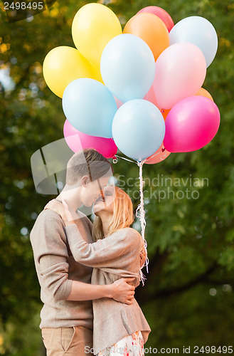 Image of couple with colorful balloons kissing in the park