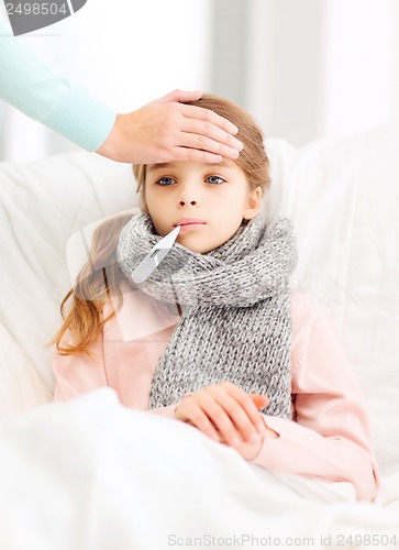 Image of ill girl child with thermometer and caring mother