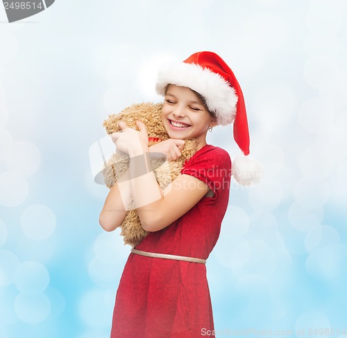 Image of smiling girl in santa helper hat with teddy bear