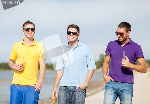Image of friends on the beach with bottles of drink