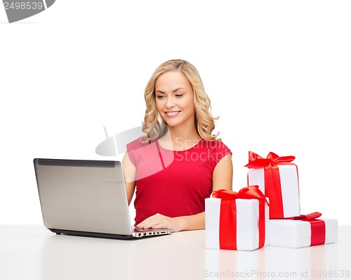 Image of woman with gift boxes and laptop computer