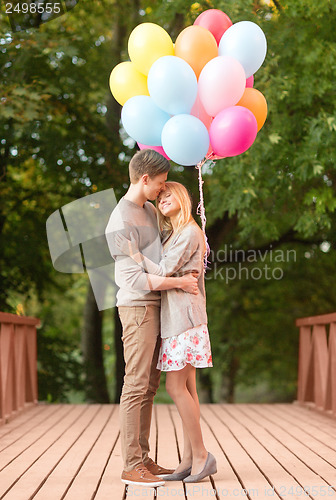 Image of couple with colorful balloons kissing in the park