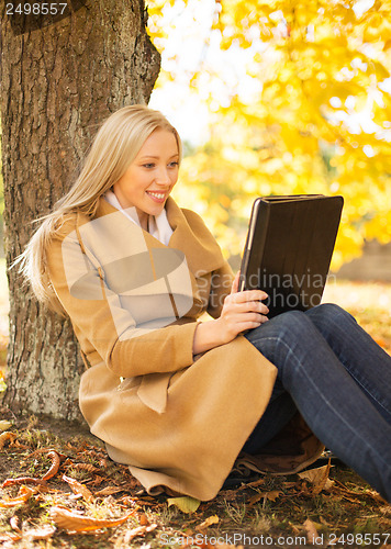 Image of woman with tablet pc in autumn park
