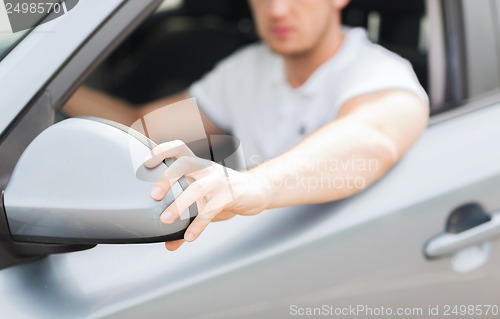 Image of man ajusting rear view mirror