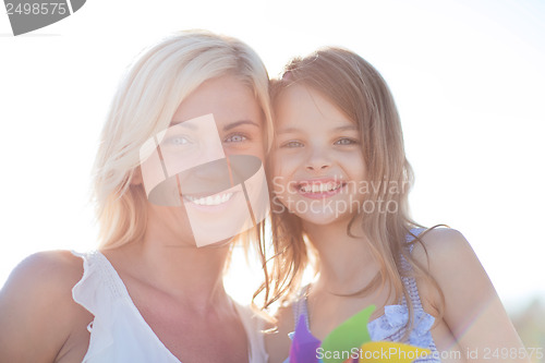 Image of happy mother and child girl with pinwheel toy