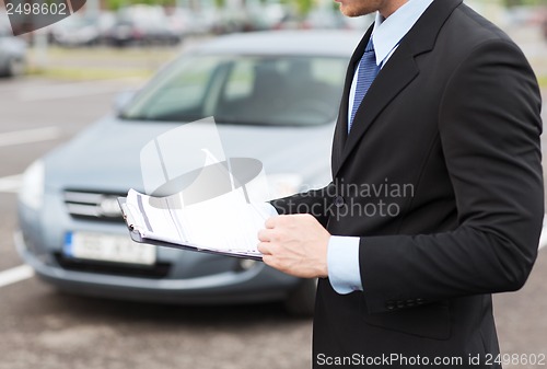 Image of man with car documents outside