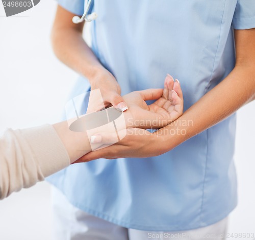 Image of nurse with patient measuring pulse