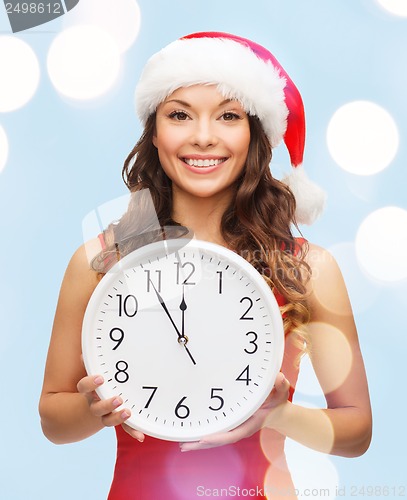 Image of woman in santa helper hat with clock showing 12