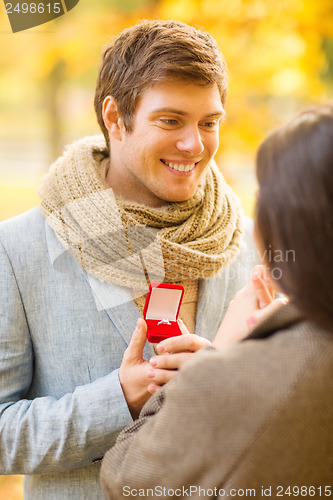 Image of man proposing to a woman in the autumn park