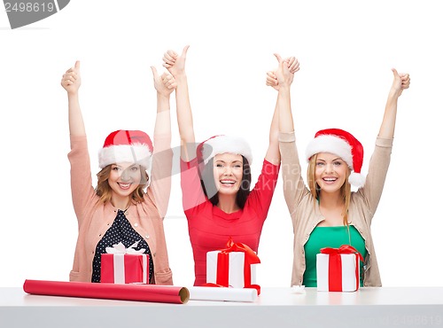 Image of smiling women in santa helper hats with gift boxes