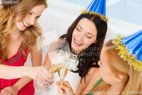 Image of three women wearing hats with champagne glasses