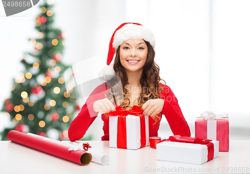 Image of smiling woman in santa helper hat with gift box