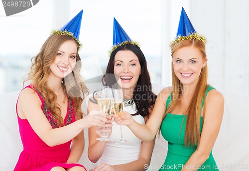 Image of three women wearing hats with champagne glasses