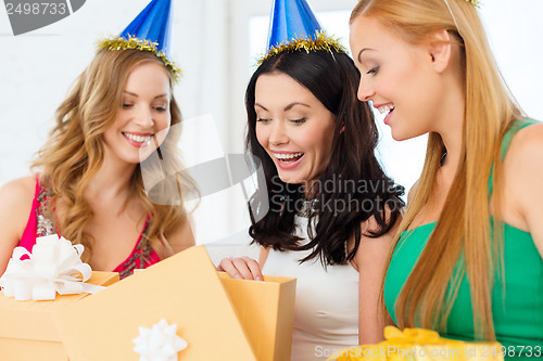 Image of three smiling women in blue hats with gift boxes