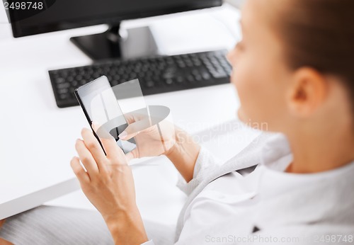 Image of businesswoman with smartphone in office