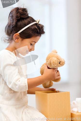 Image of happy child girl with gift box and teddy bear