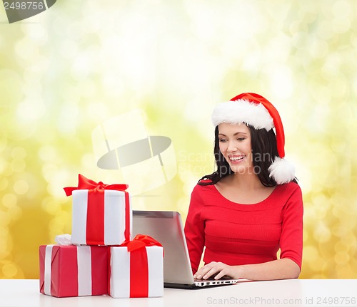 Image of woman with gift boxes and laptop computer